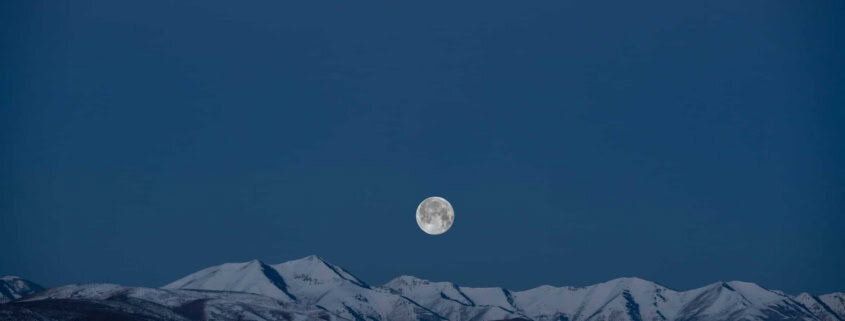 Vollmond über den schneebedeckten Bergen