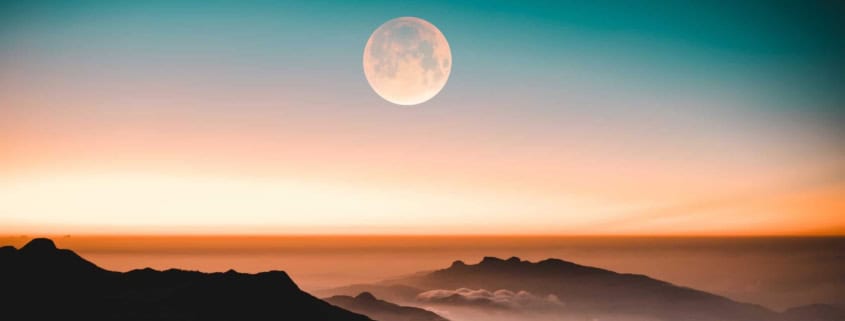 Vollmond über Bergen in farbigem Himmel